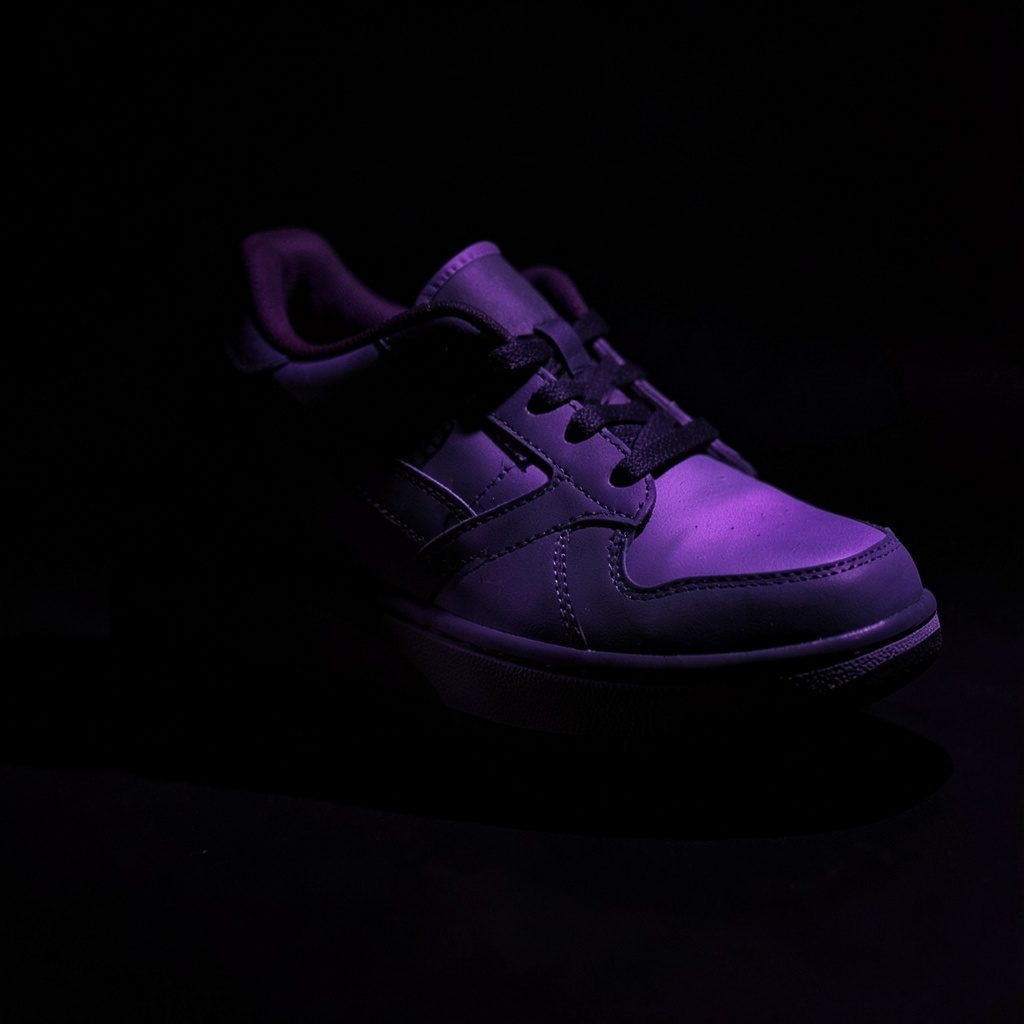 Golden Goose sneaker in yellow and white colorway with signature star patch, photographed in moody low-light against a dark surface